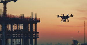 Drone flying near a building under construction at sunset