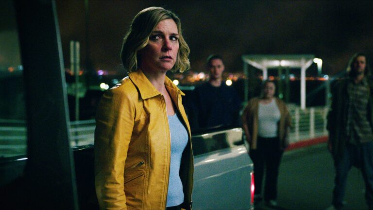 Carol looking worried as she stands next to a truck surrounded by people in Pluribus episode 1