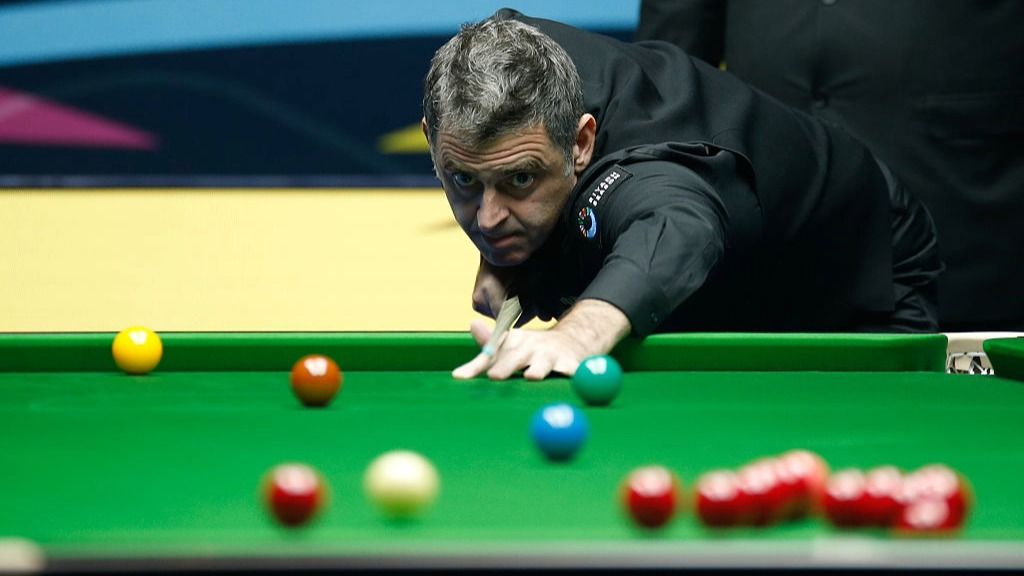 Snooker player Ronnie O'Sullivan takes a shot, with red, yellow, green, brown and blue balls visible