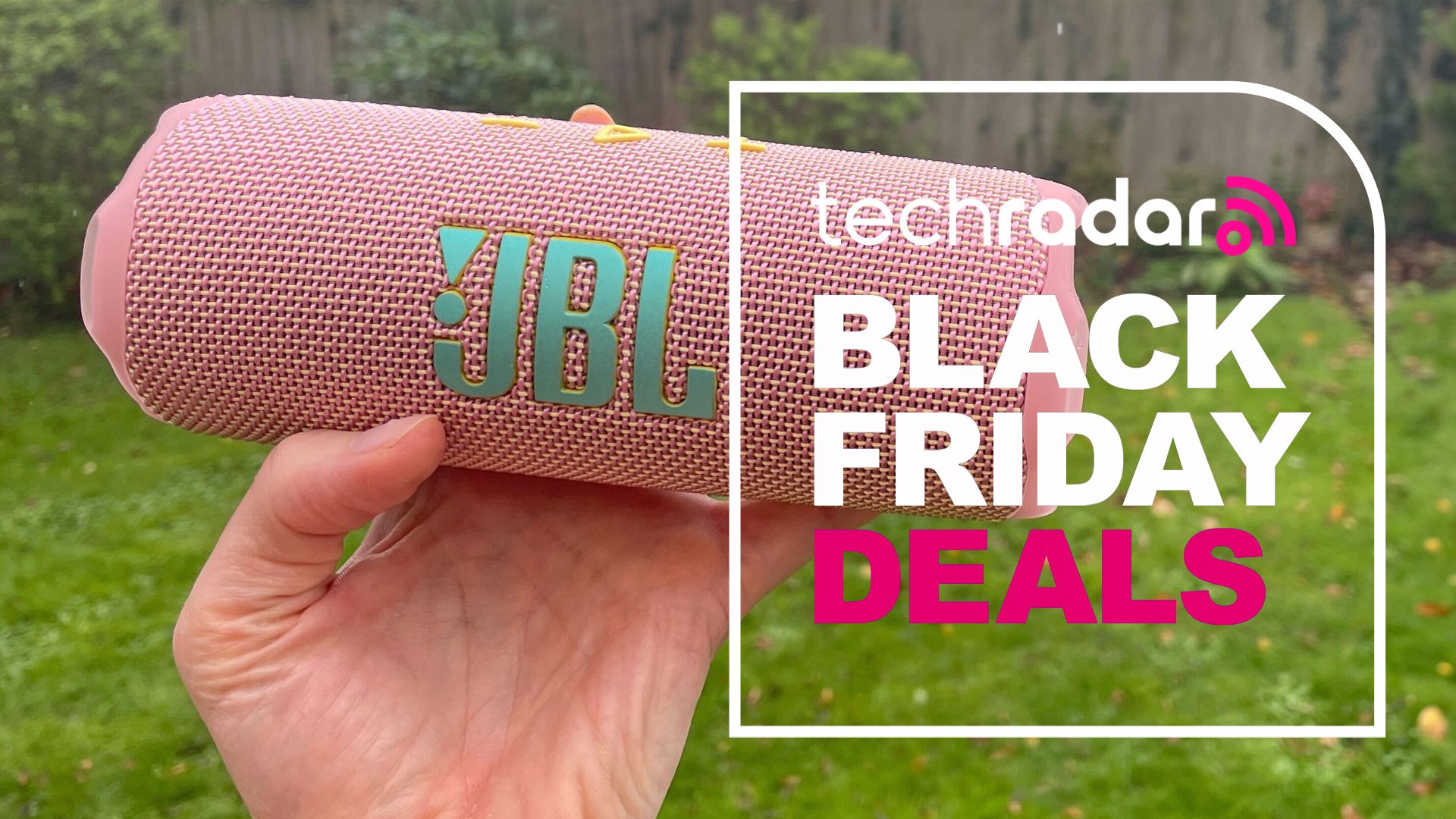 A woman's hand holding the JBL Flip 7 outdoors, with a sign saying Black Friday DEals