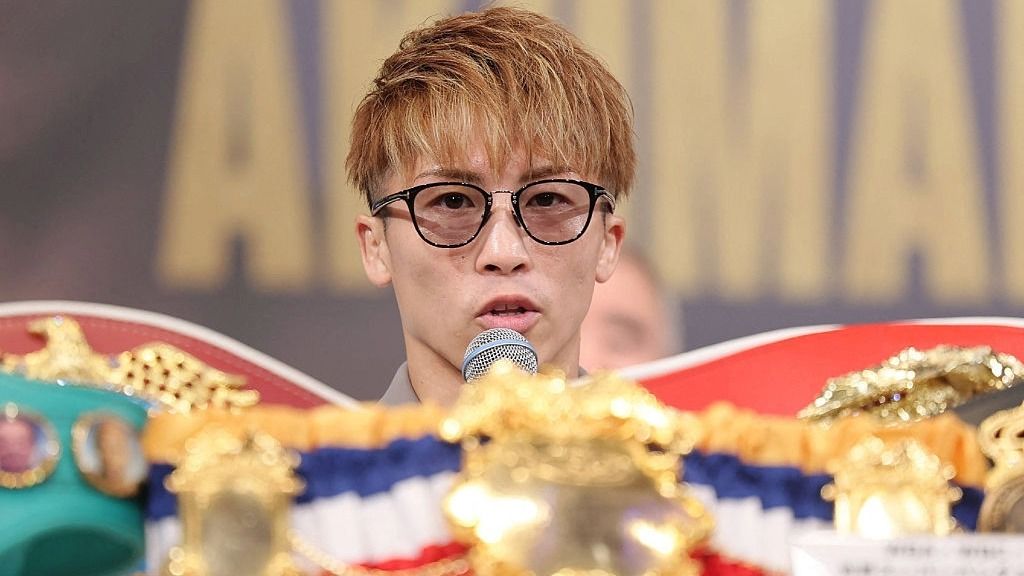Undisputed world super bantamweight champion Naoya Inoue speaking at a press conference in front of his belts.