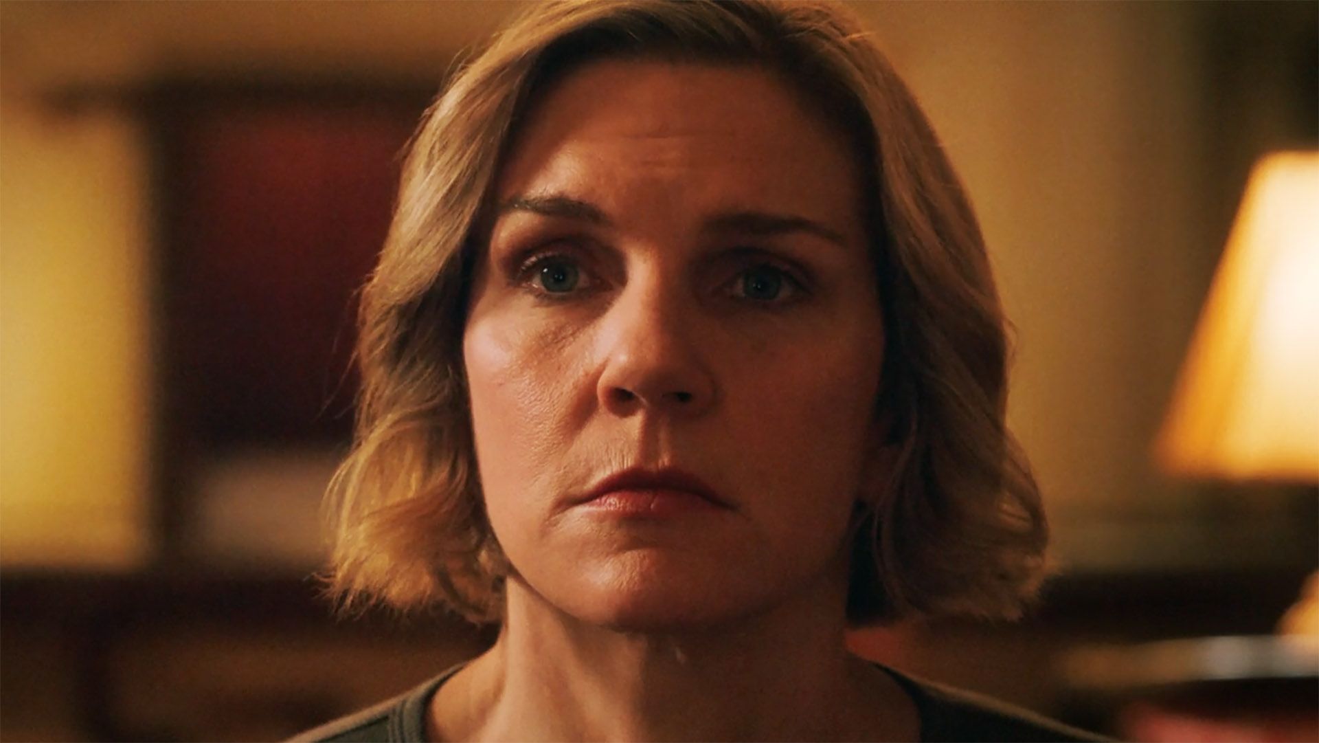 A close up of Carol looking at an off-screen TV in Pluribus episode 5