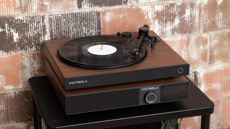 The Victrola Soundstage under a Victrola turntable, on a table by a brick wall.