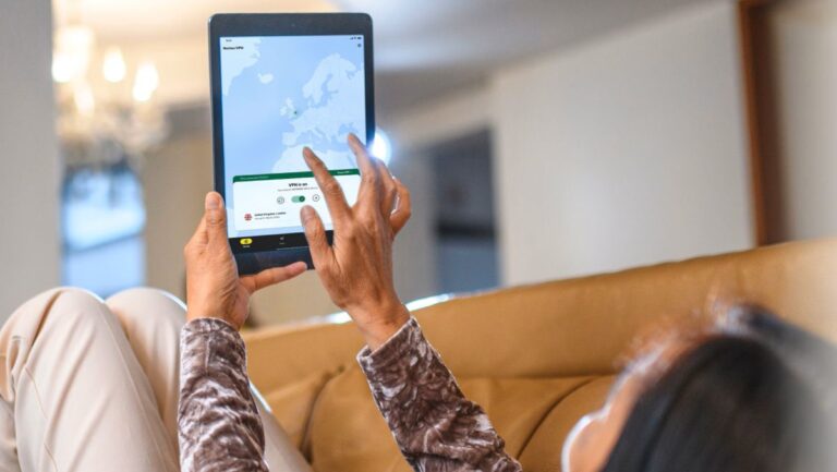 A woman laying back on a sofa and using Norton VPN on her tablet.