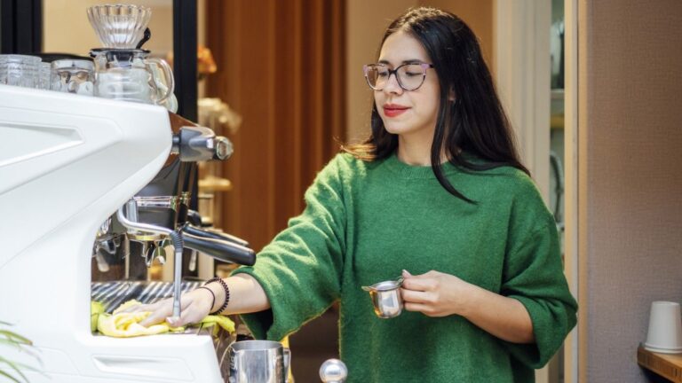 Woman wiping coffee maker drip tray with cloth