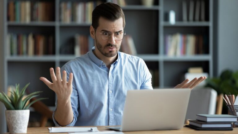 Young man looking frustrated sitting in front of a laptop