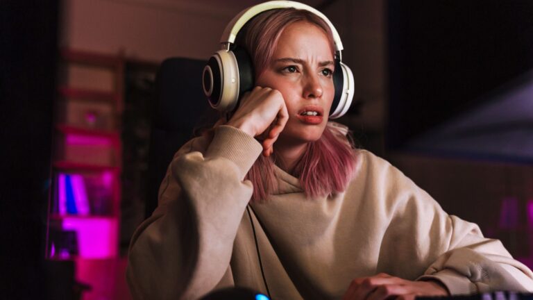 A frustrated looking PC gamer wearing headphones