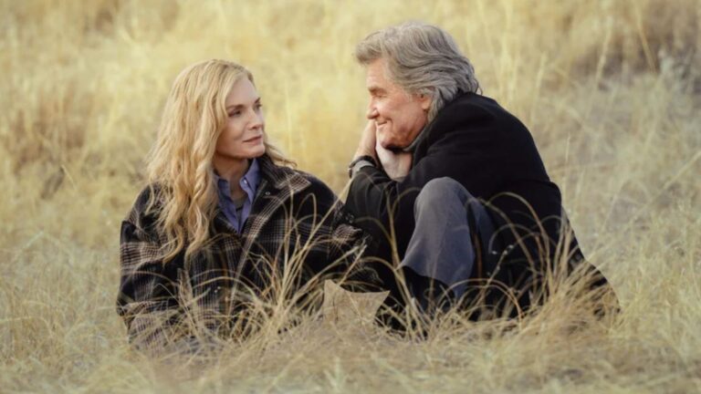 Michelle Pfeiffer and Kurt Russell sit in the middle of a grassy field