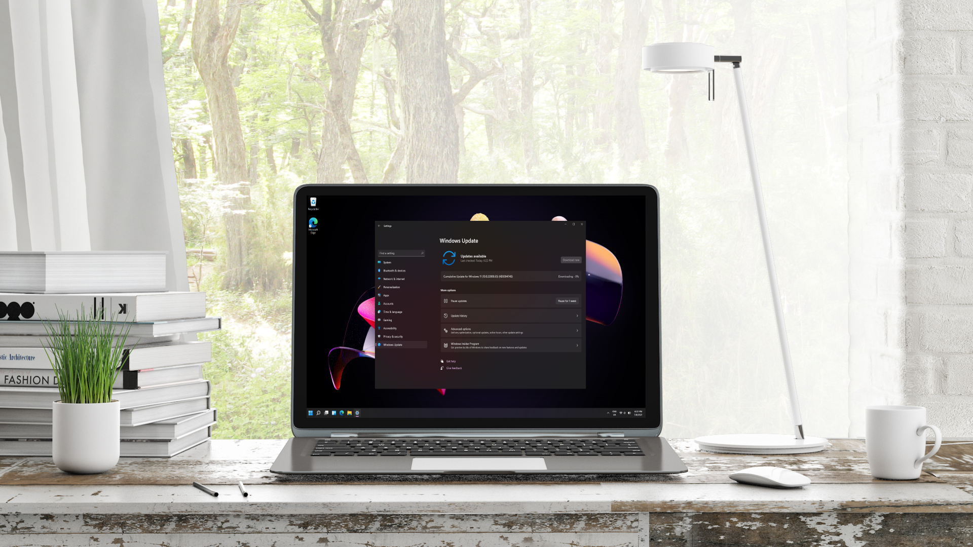 Windows 11 Update showing on laptop on a desk in front of a window