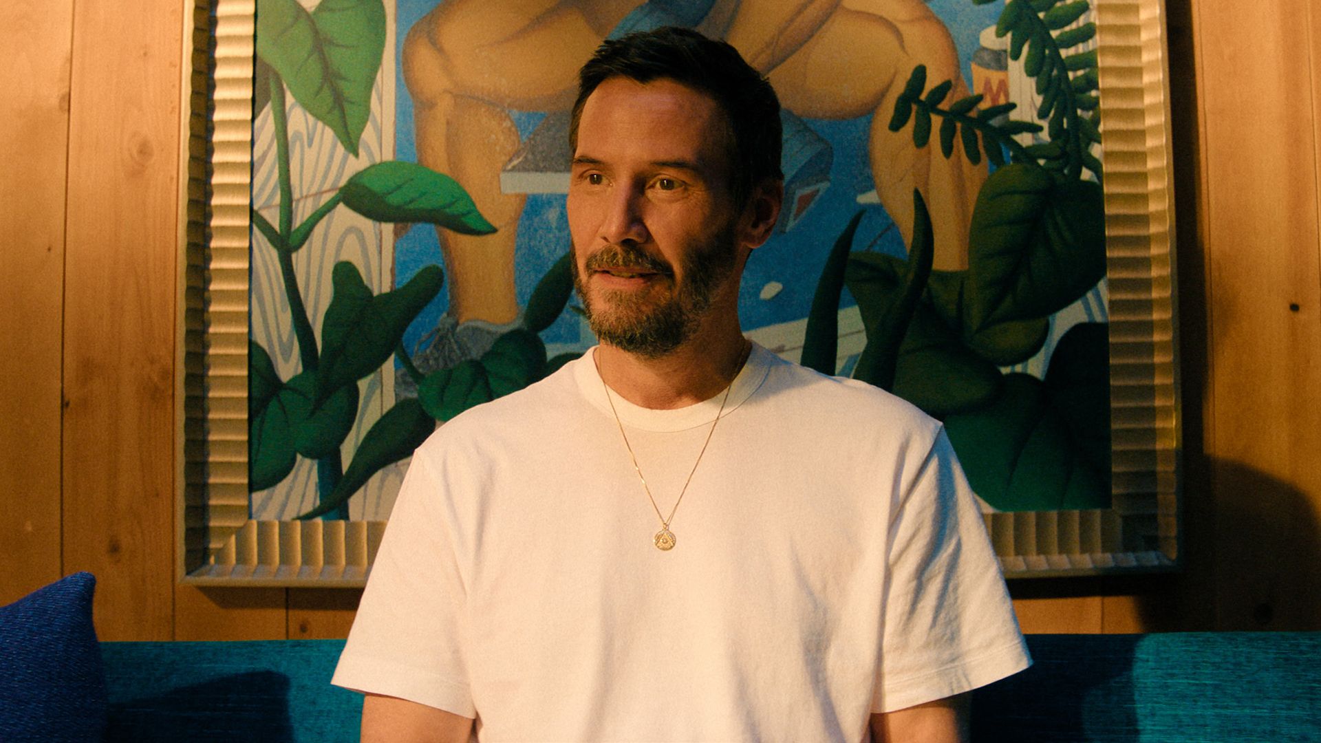 Keanu Reeves' Reef sitting on a couch in Apple TV's Outcome movie