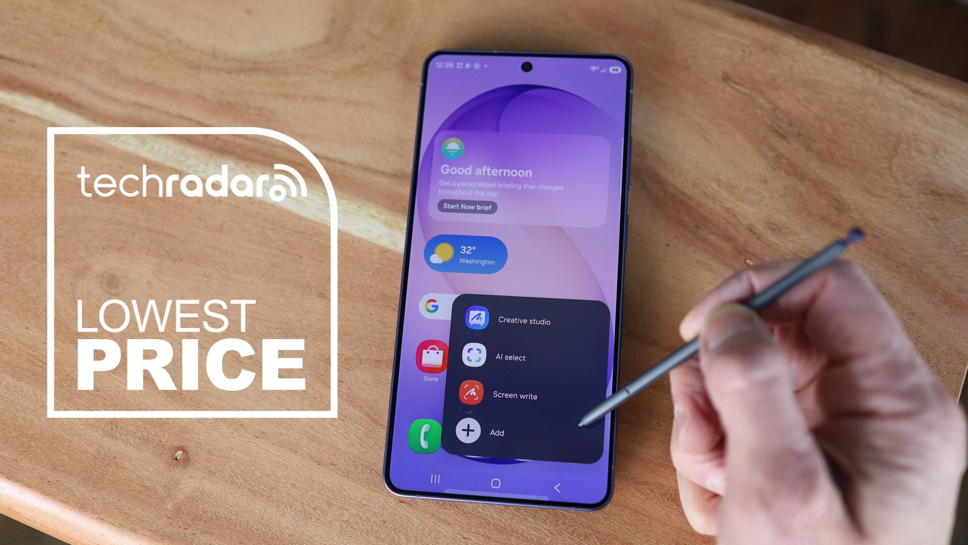 Samsung Galaxy S26 Ultra on desk top with person holding S-Pen, alongside a lowest price text overlay