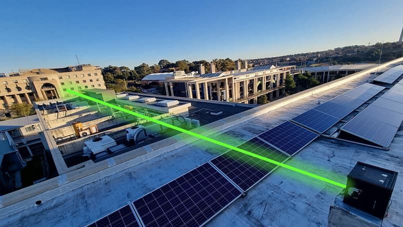 A green beam of light is fired from an internet device on a rooftop.