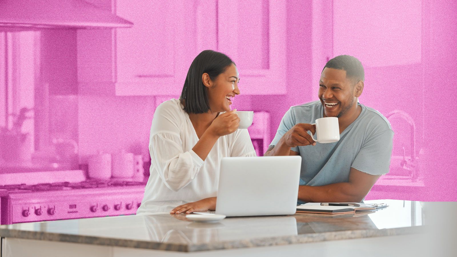 Young couple drinking coffee in a kitchen and smiling. A laptop is on the kitchen island.