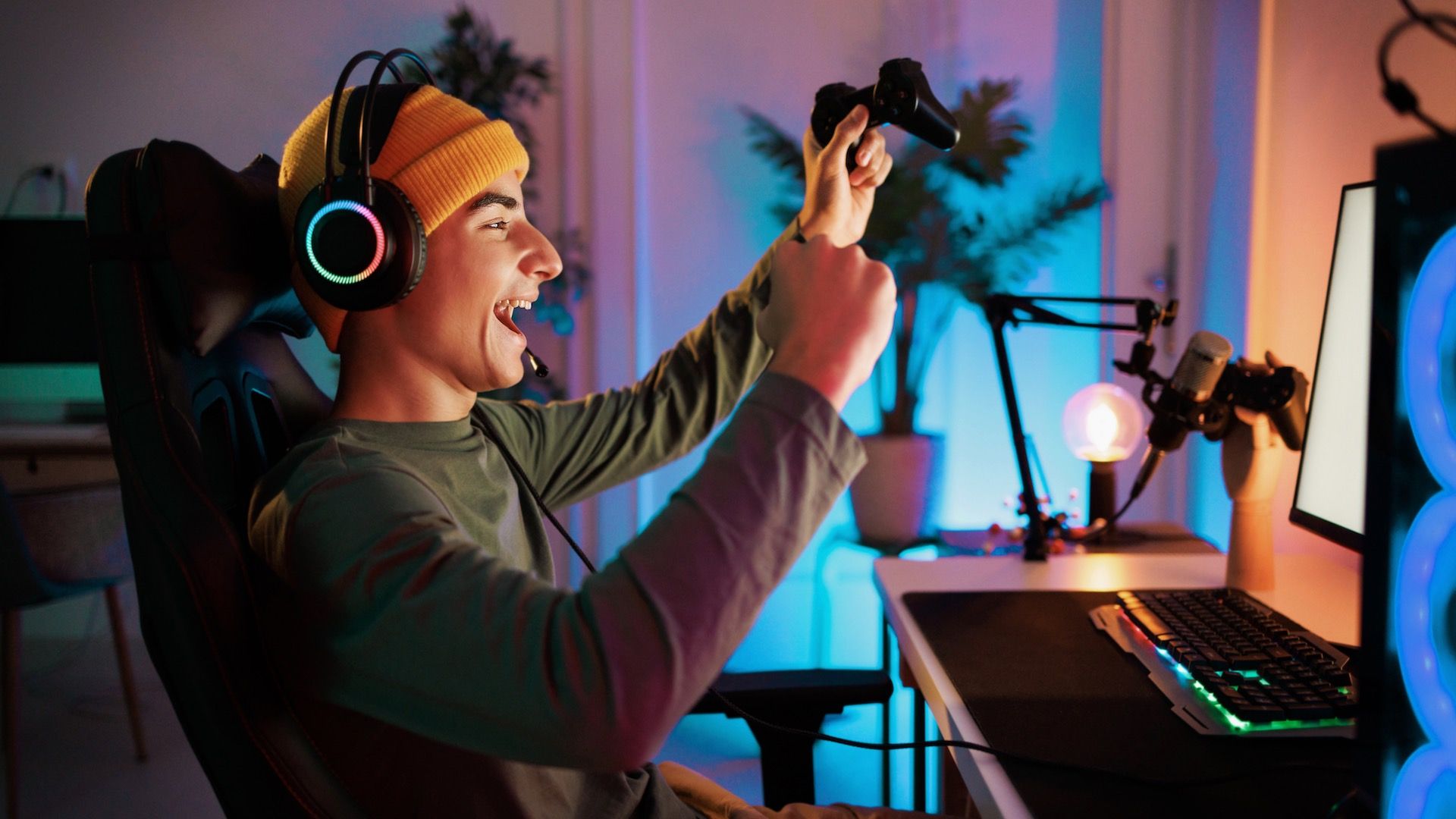 A young teenager is playing a PC game and celebrating