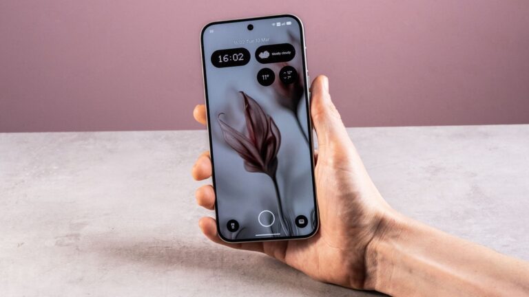 A man's hand holding the Nothing Phone (4a) Pro showing its home screen.