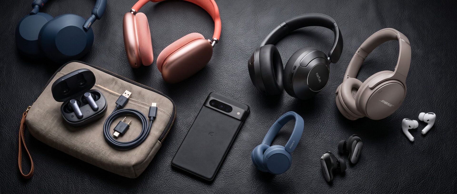 A selection of headphones and earbuds on a black desk