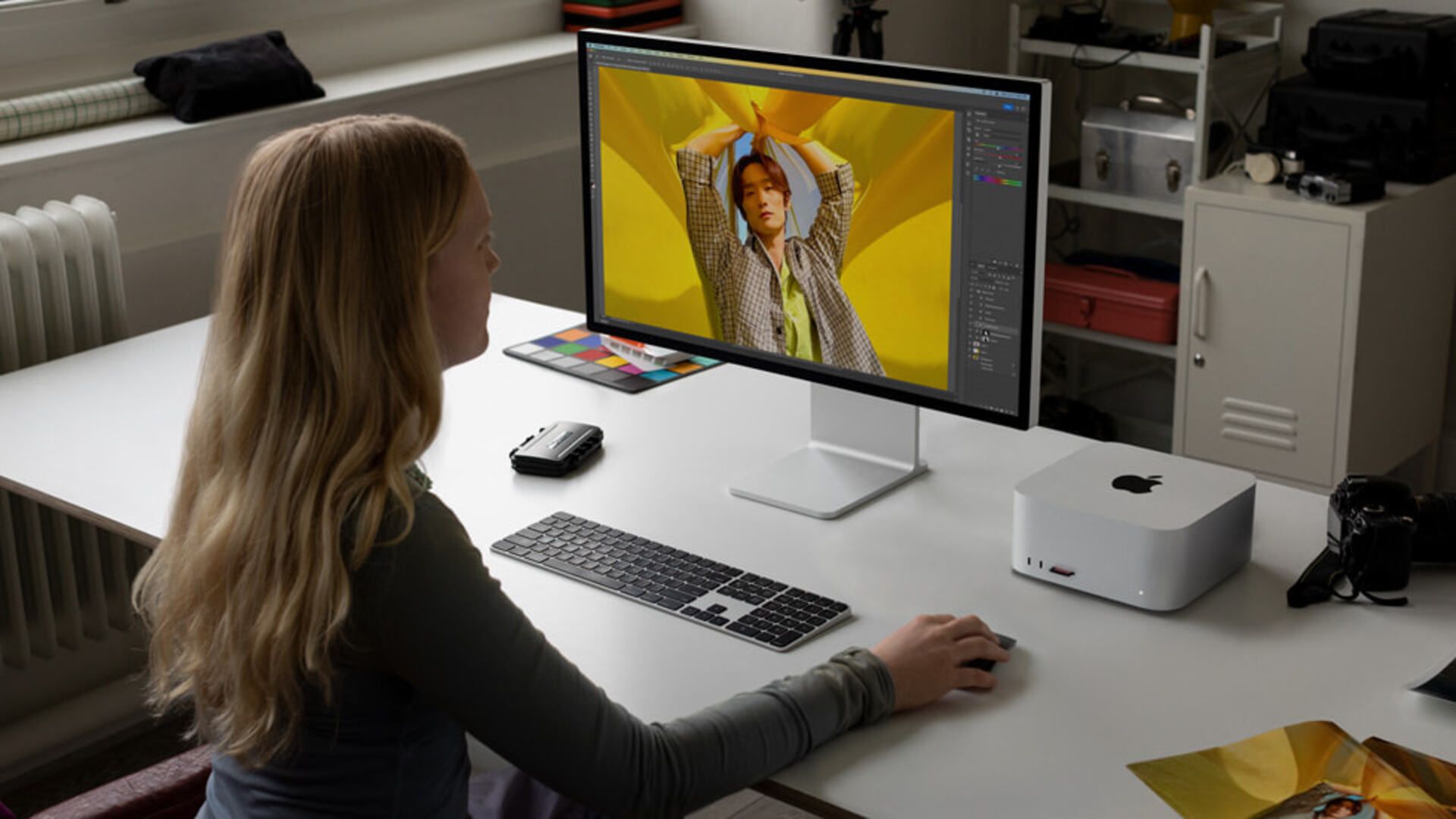 A woman using a Apple Mac Studio and Studio Display on a desk in an office