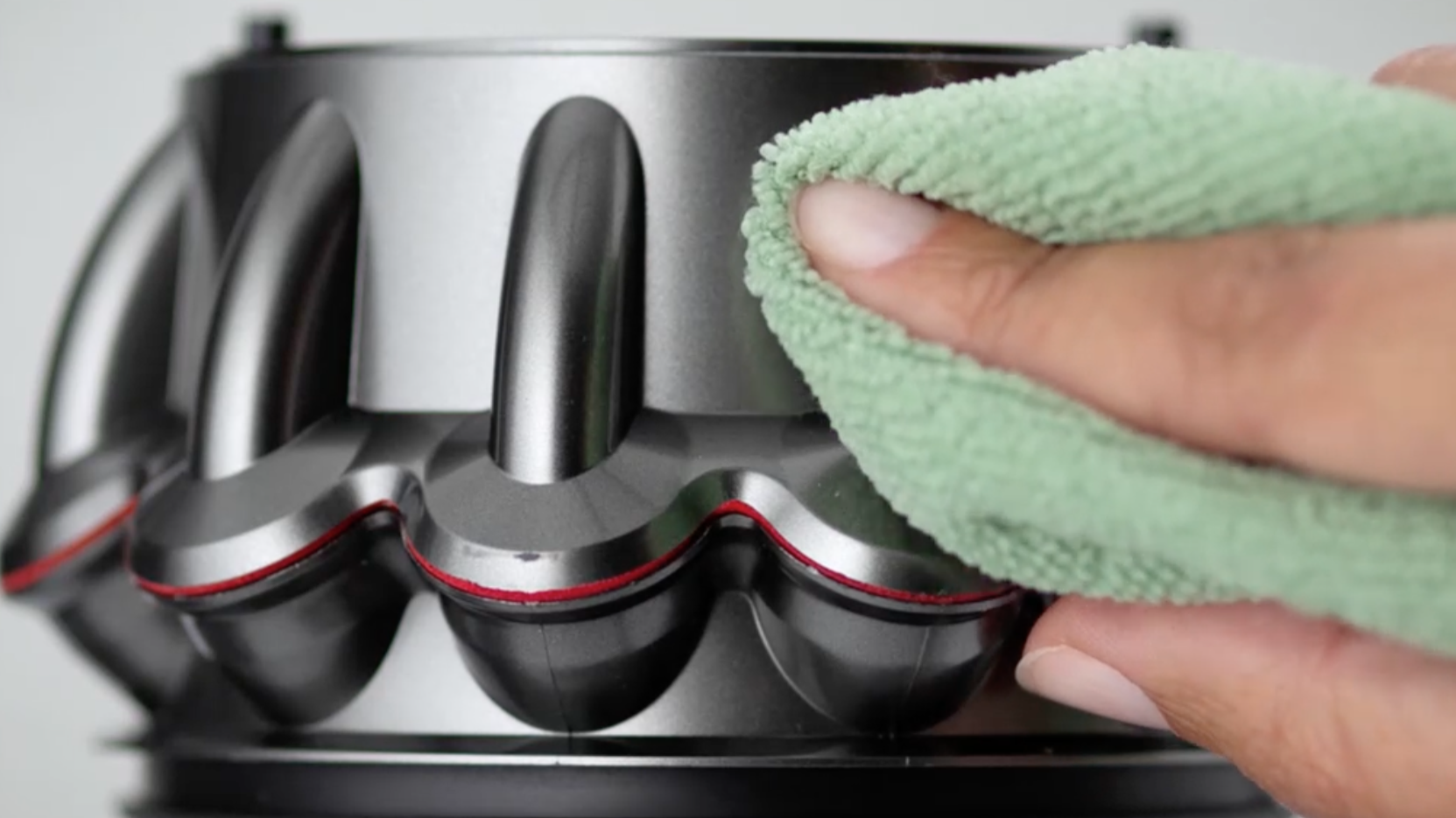 Person cleaning Dyson vacuum cleaner with a cloth