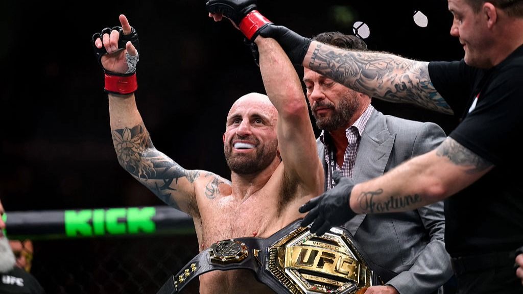 Alex Volkanovski, with the UFC title around his waist, celebrates a victory.
