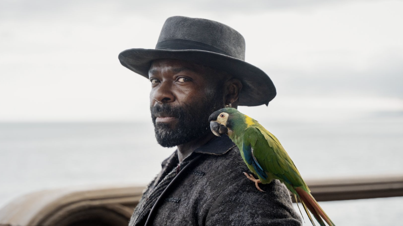 David Oyelowo as Long John Silver with a parrot on his shoulder
