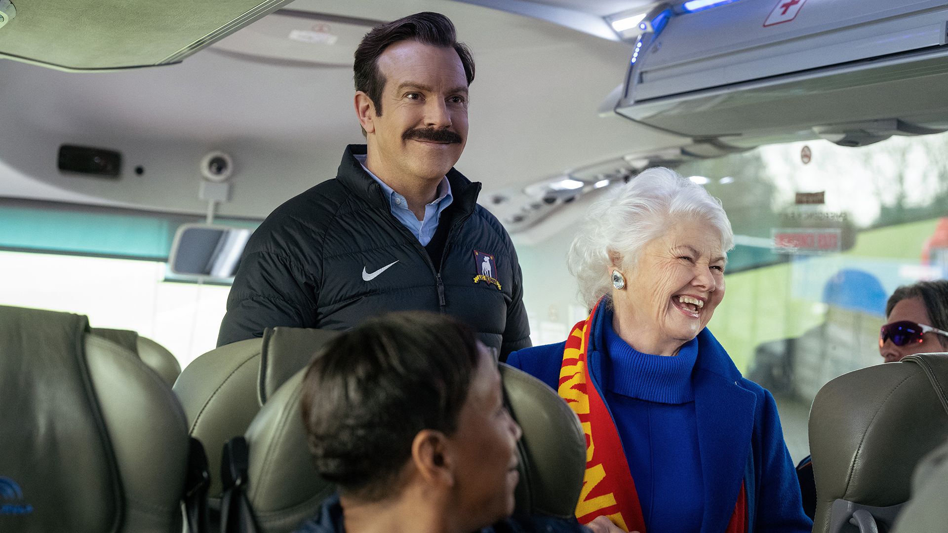Ted and Mae smiling as they board a coach in Ted Lasso season 4 episode 9